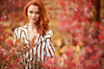 Smiling redhead outdoors backlit by sun, fashion shoot. Close up woman portrait . redhair girl. Beautiful young woman close-up in autumn .