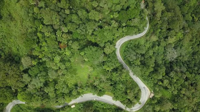 From above mountain bend road in green forest. Travel on car tourism. Unique aerial drone view. Asia Malaysia highlands. Sunny day