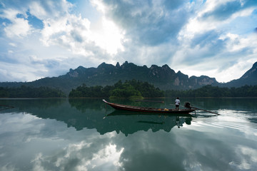 Fisherman in a boat on the river. Man with sail  in the boat. In calm water reflection mirror with fog over the lake.