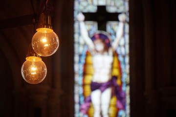 Picture of yellow bulbs in fron of colorfull mozaic windos in the church