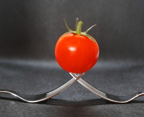 Eine reife rote Tomate auf zwei Gabeln
