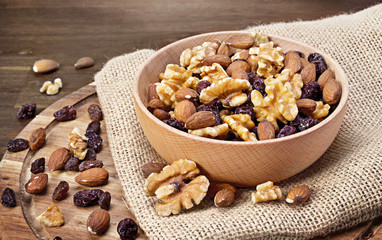 Delicious nuts arrangement in a wooden bowl. Close up shot of various nuts, healthy eating scene and wooden table.