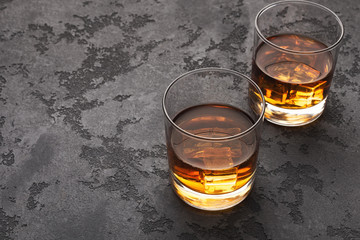 Two glasses of scotch whiskey on black marble table