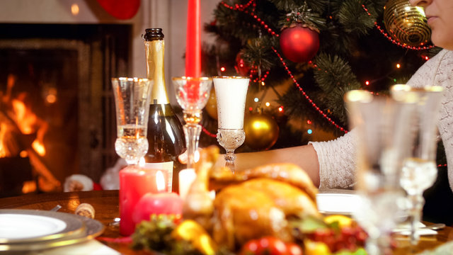 Closeup image of young woman taking bottle of champagne on Christmas family dinner