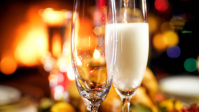 Closeup image of two champagne glasses being filled on Christmas family dinner