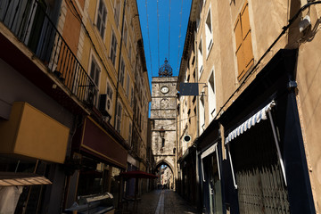 low angle view of cozy narrow street and old historic clock tower, provence, france