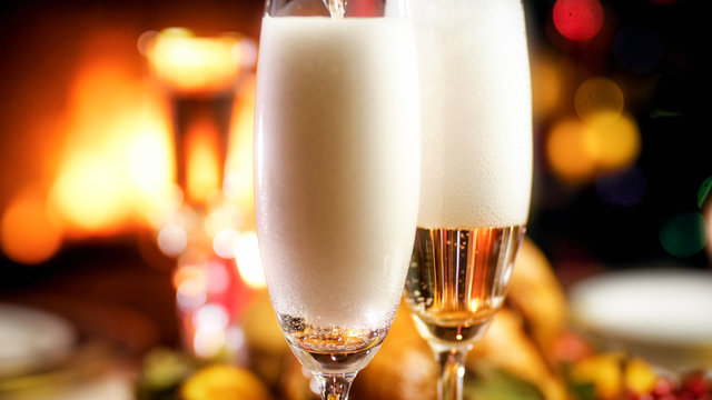Closeup image of filling two glasses with champagne on romantic dinner at night