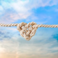 White rope in heart shape knot on background. Love concept.