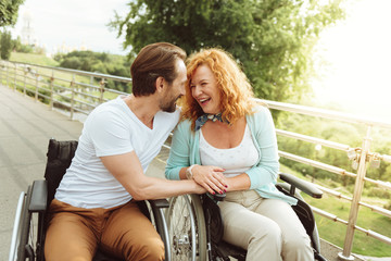 Never bored together. Joyful disabled people looking at each other and smiling cheerfully while...