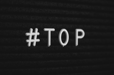 Hashtag word #top written on the letter board. White letters on the black background
