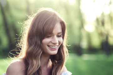 Fototapeta premium Close-up portrait of a beautiful girl in a white dress at sunset in summer. 