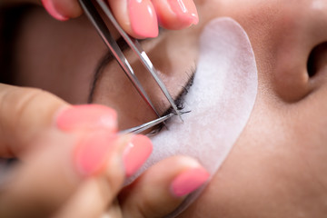 Beautiful Woman with long eyelashes in a beauty salon. Eyelash extension procedure - obrazy, fototapety, plakaty