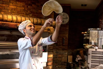 Foto op Plexiglas Bekwame chef-kok bereidt deeg voor pizza die met handen rolt en overgeeft © V&P Photo Studio