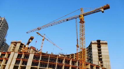 Fototapeta na wymiar Construction site. Three cranes near building.