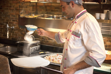 Skilled chef preparing  pizza rolling with hands
