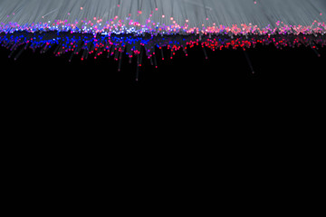 Glowing blue red optical fibres close up macro shot on reflecting dark surface, space for text.