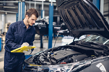 Auto car repair service center. Mechanic examining car engine