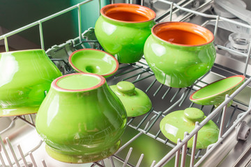 Four green ceramic pots lie in the lower compartment of the dishwasher