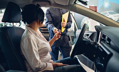 Car service center scene. The mechanic giving car key to the client