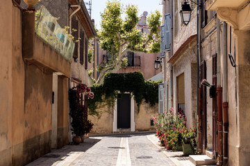 Fototapeta na wymiar cozy narrow street with traditional houses and blooming flowers in pots, provence, france