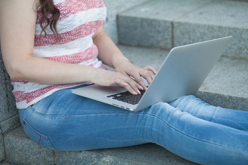 Naklejka premium Young beautiful woman with laptop sitting on stairs near the university