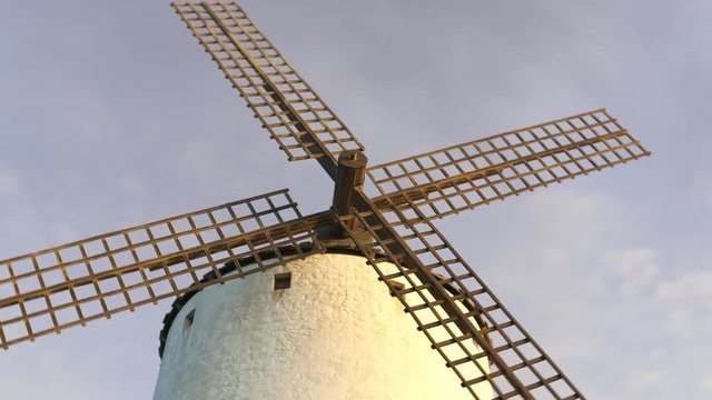 Closeup shot of a vintage Spanish windmill's wings rotating slowly at sunset. 4K
