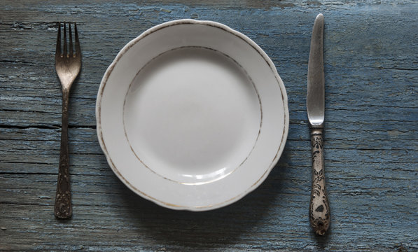 Empty Plate, Fork and Knife on wooden background.