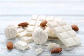 Chocolate pieces with coconut candies and almonds on wooden table