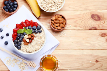 Oatmeal with berries and nuts in bowl on wooden table