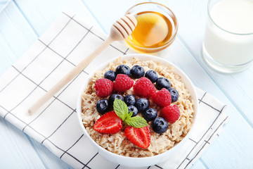 Oatmeal with berries in bowl on wooden table