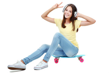 Young girl sitting on skateboard with headphones