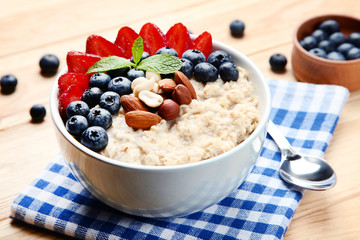 Oatmeal with berries and nuts in bowl on wooden table