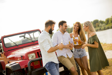 Young people drinking and having fun by car