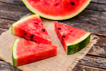 Slices and half of fresh watermelon on wooden board