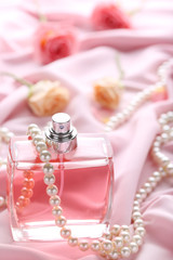 Perfume bottle with roses and bead on satin background