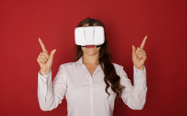 Young woman in virtual reality (VR) glasses. Isolated on red background