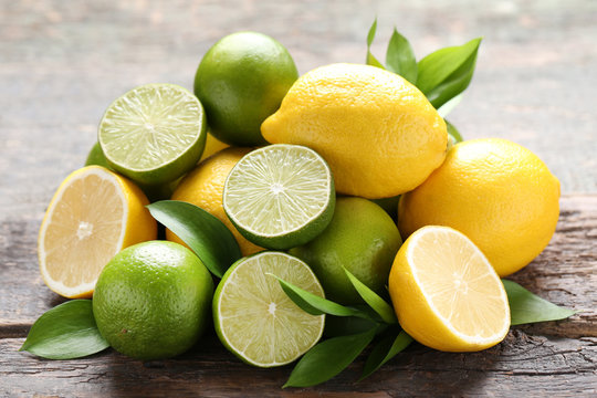 Lemons and limes with green leafs on grey wooden table