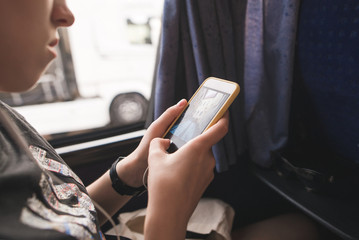 Tourist girl sits in the bus near the window and uses a smartphone. Using a smartphone on a trip....