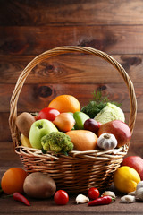 Ripe fruits and vegetables in basket on wooden table