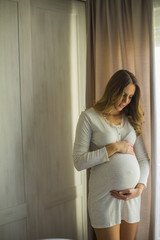 Fototapeta premium Young pregnant woman by the window