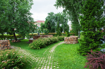 Fototapeta premium Piękny letni park krzewów, drzew i kwiatów droga wyłożona kamieniem