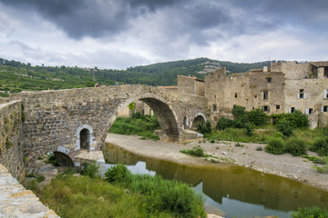 Fototapeta premium La antigua arquitectura histórica que incluye el famoso puente sobre el pequeño río de montaña en el pueblo medieval Lagrasse, el pueblo más hermoso de Francia.