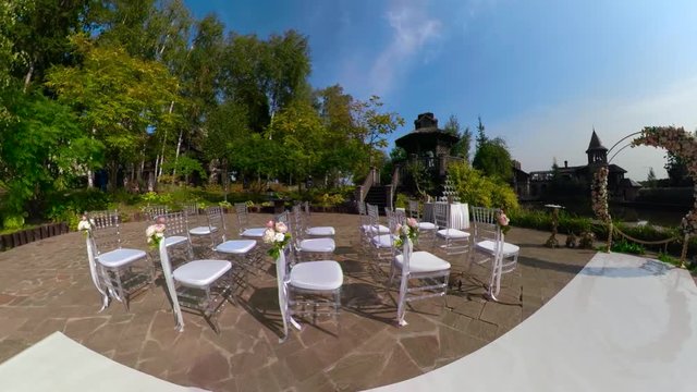 wedding ceremony with arch decorated with cloth and flowers outdoor. wedding set up in the park on a sunny day, arch and chairs for guests