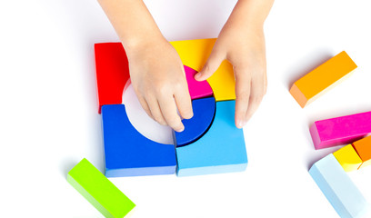 A child plays with colored blocks, colored cubes constructs a model on white background