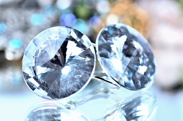 Close-up of transparent earrings jewels - reflection effect - colored backgrounds