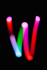 Letter W. Glowing letters on dark background. Abstract light painting at night. Creative artistic colorful bokeh. New Year. Use it for build you own design for book cover, CD, poster or post card.