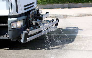Municipal truck cleans the roadway with a jet of soap and water