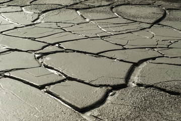 cracked wet clay on the bottom of a dry pond in an arid area