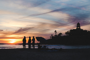 Friends standing on a Mexican beach watching a sunset.