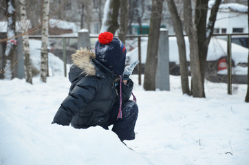 Fototapeta na wymiar Baby boy walking at snowfall. Child in winter clothes playing with snow